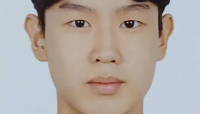Photo of a young Korean boy from the shoulders up. He is wearing a black top and has dark brown hair and brown eyes.