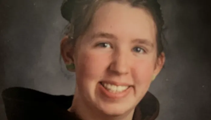 Shoulders-up school photo of a smiling girl with white skin and brown hair that's pulled back in two buns.