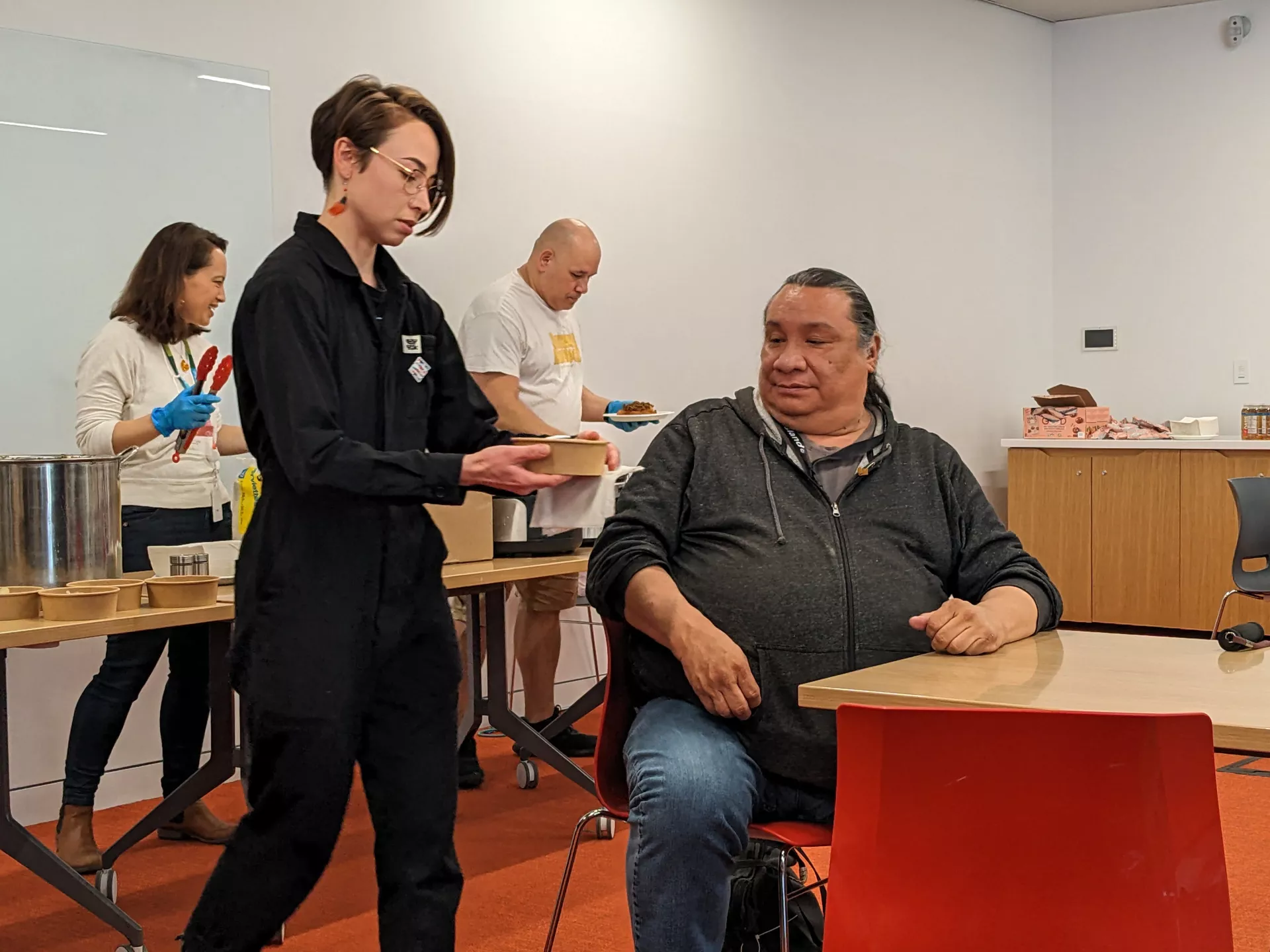 Tamara Cardinal serves the first traditional Indigenous stew to Elder Adrian Wolfleg.